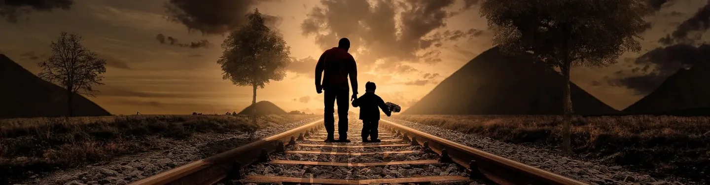 Mężczyzna z dzieckiem idący po torowisku